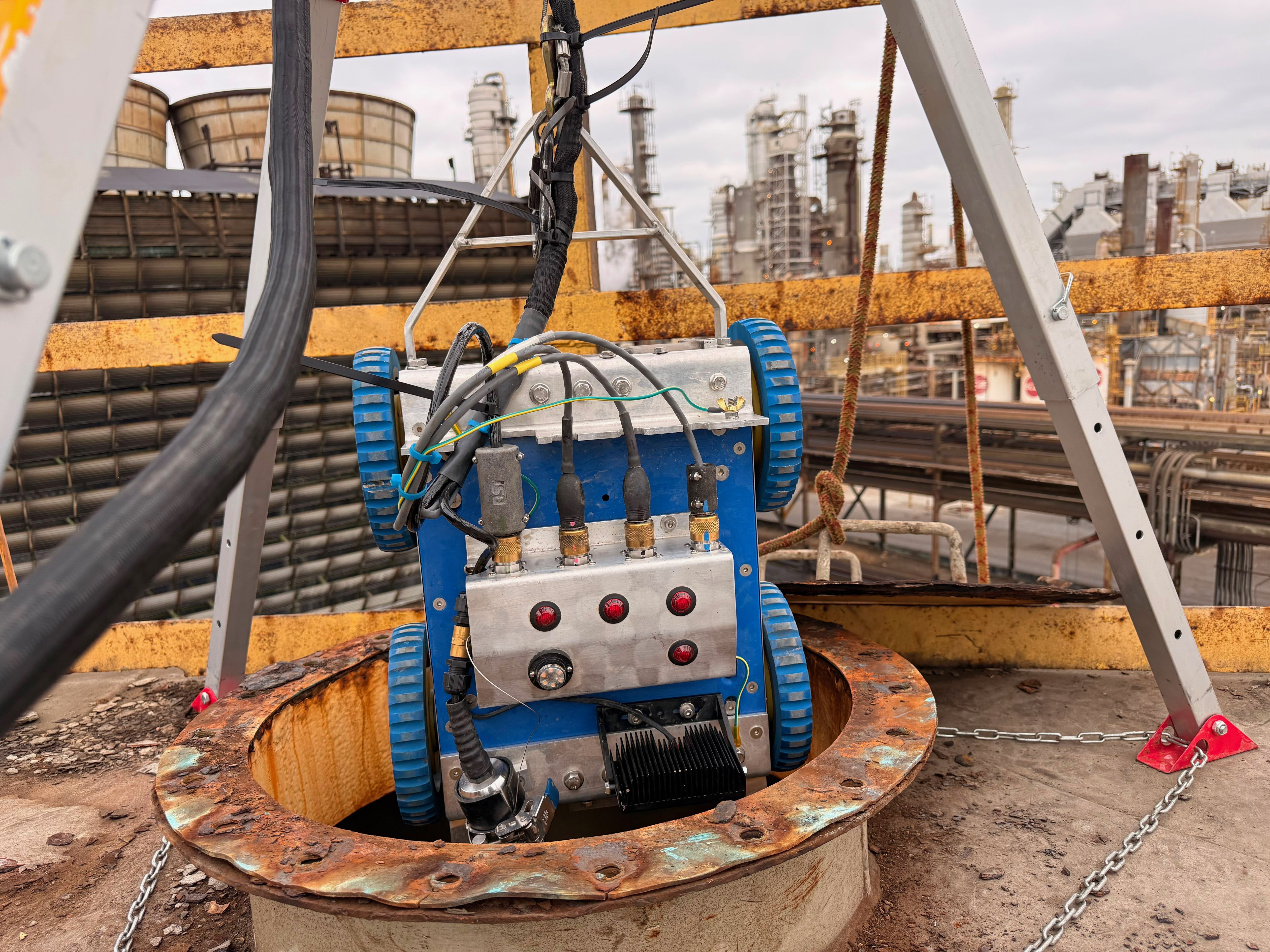BSI Scavenger 3.0 robotic ultrasonic scanner being deployed through a tank roof manway with tripod rigging